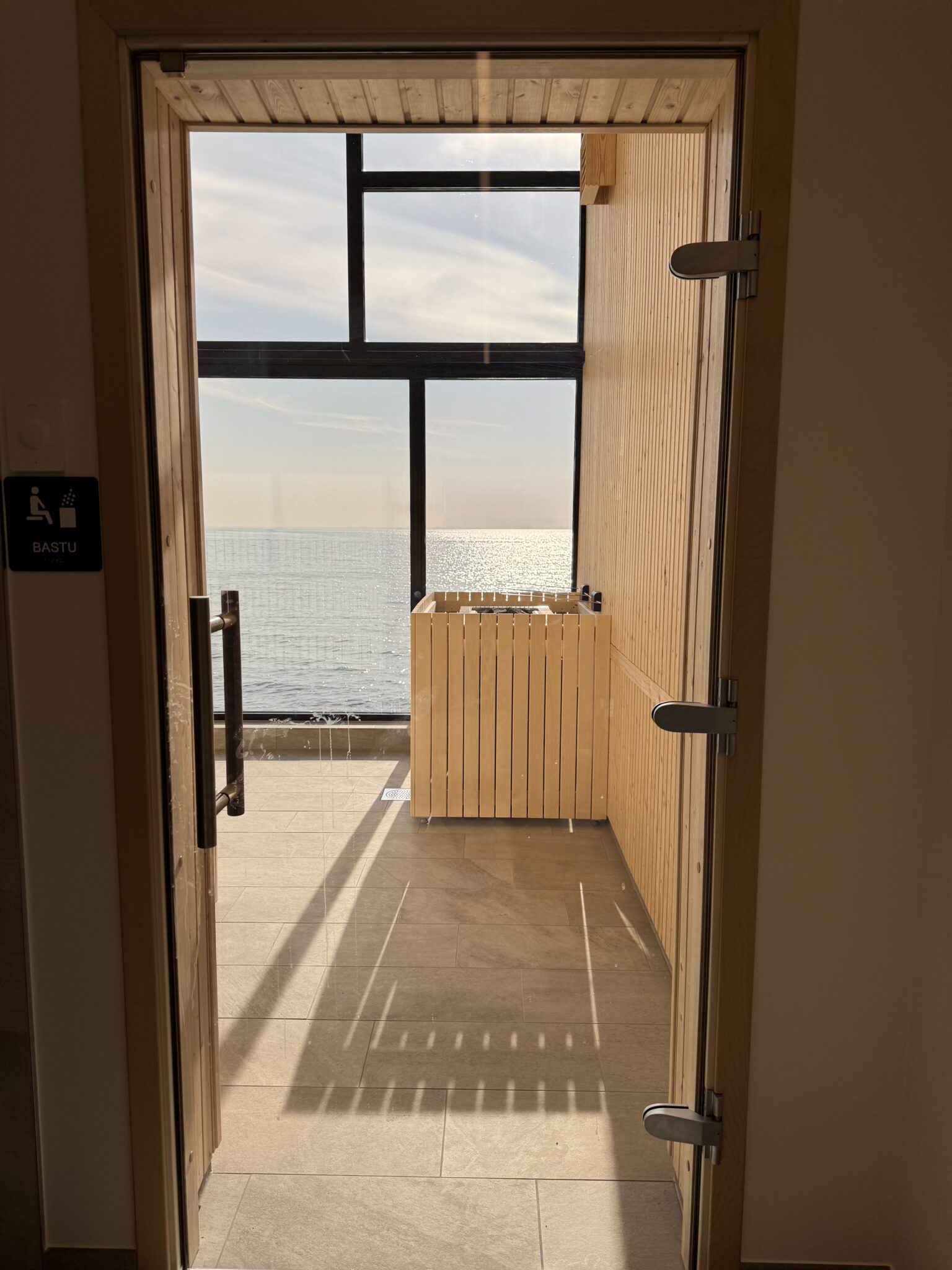 Glasdörr in till bastun med utsikt över havet.